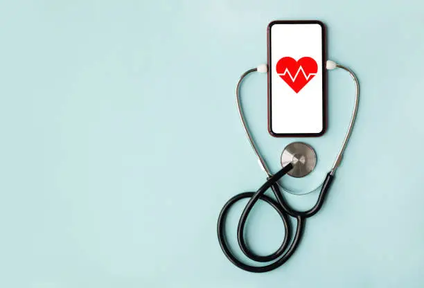 Photo of Mockup medical stethoscope and mobile smart phone heart beats isolated on blue background. Copy space.