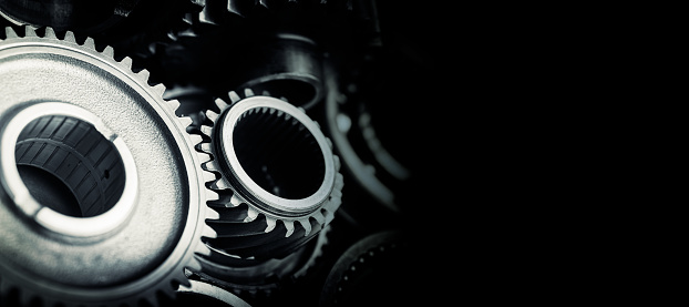 Blue tint black industrial gears and cogs on black background, banner copy space