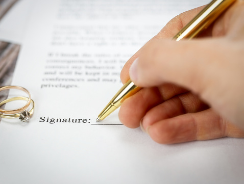 Marriage contract with two golden wedding rings and gold pen, prenuptial agreement, macro close up, sign with signanture,document,agreement concept romance