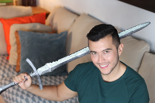 Young hero holding a sword at home.
