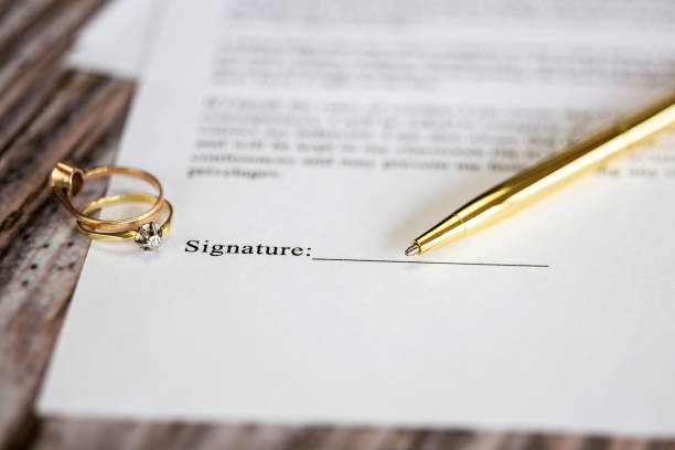 Marriage contract with two golden wedding rings and gold pen, prenuptial agreement, macro close up, sign with signanture,document,agreement concept stock photo