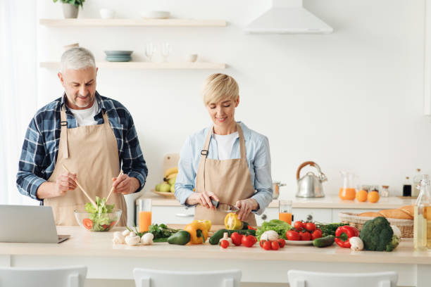 istock Couple preparing healthy vegetarian salad, enjoying process on modern cozy kitchen, cooking together 1309245542