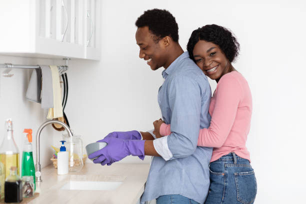 istock Black woman hugging her husband washing dishes 1309245819