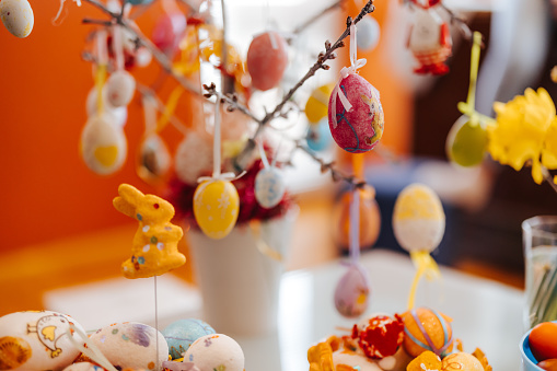 Easter decoration- Easter eggs in basket and hanging on Easter tree and daffodil flowers on the table