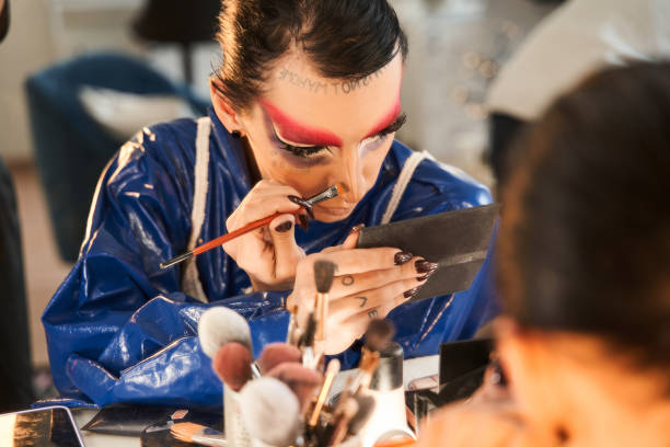 istock Drag queen looking at the hand mirror and applying makeup at his face 1309247033