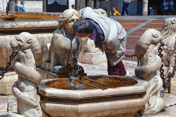 ignoto beve acqua dalla fontana storica (fontana del contarini) in piazza vecchia sant'alta bergamo (citta alta). - thrist foto e immagini stock