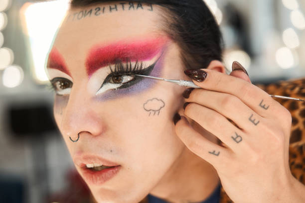 istock Drag queen with false eyelashes and septum at his nose looking at the mirror 1309247036