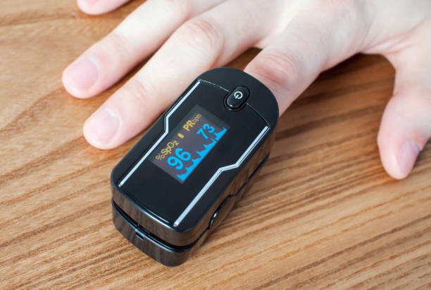 pulse oximeter on the index finger on a wooden background. measurement of blood oxygen and pulse. close-up - taking pulse oximeter medical oxygen equipment human lung imagens e fotografias de stock