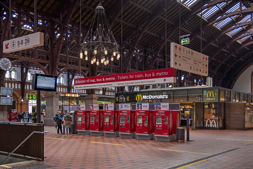 Ticket machines in the main railway station in Copenhagen looks like a clash between modern and old - the machines contra the wooden construction and the chandelier