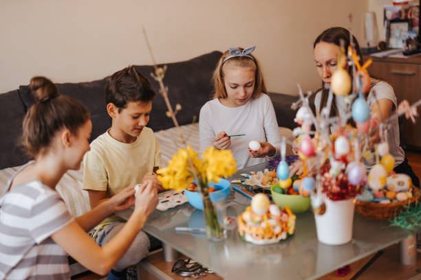 istock Happy family decorating Easter eggs at home 1309248549
