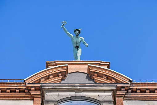 Statue of Hermes  - god of thieves and merchants - on the roof of a high building. This is an ornament on a house in the central Copenhagen from around year 1900 in the pedestrian district in the center of the city