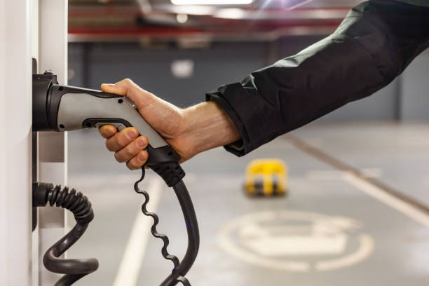 istock Man charging electric car at charging station 1309249074