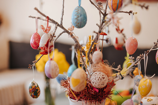 Easter eggs painted in pastel colors on a white background with copy space and cute spring flowers, Happy Easter Holiday concept with space for text. Yellow pink and blue bright colors