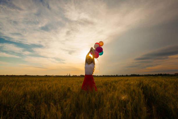 portrait d’une femme tenant des ballons contre le ciel - sun sky child balloon photos et images de collection