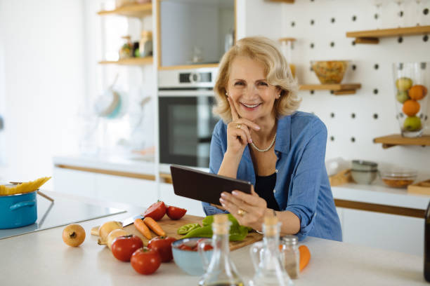 istock Senior woman using digital tablet in the kitchen, looking for recipe on internet 1309252636