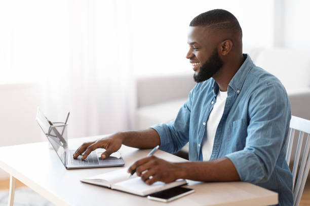 istock Online Education. Young Smiling Black Guy Study With Laptop At Home 1309255435