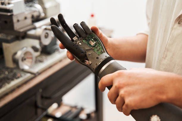 mann hält bionische hand bei der entwicklung von prothesen künstliche gliedmaßen - prothese stock-fotos und bilder