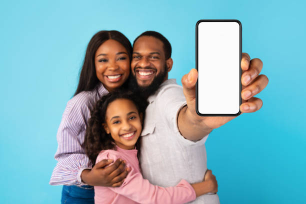 famiglia nera che mostra lo schermo vuoto dello smartphone vuoto per il mockup - child telephone mobile phone little girls foto e immagini stock