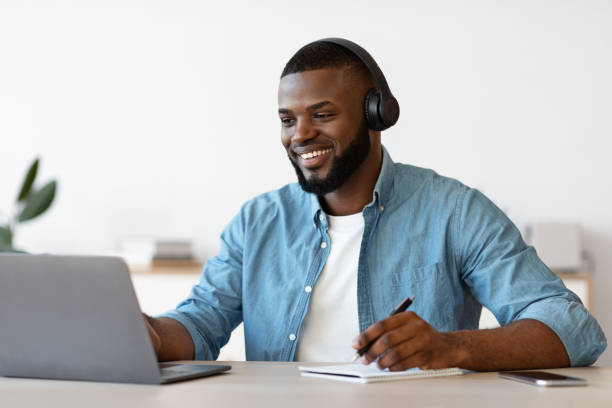 istock Online Education. Black Guy In Headphones Study With Laptop And Taking Notes 1309255691