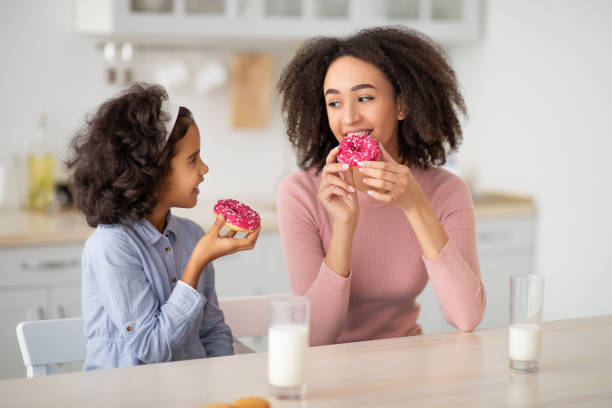istock Black mother and daughter eating sweets in kitchen 1309256507