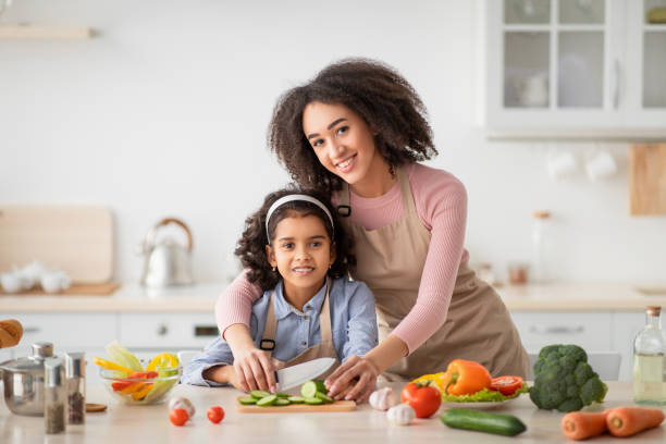 istock Cheerful black mom teaching daughter how to prepare salad 1309256842