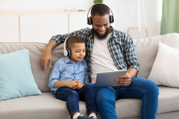 istock Black Father And Little Son Using Tablet Wearing Headphones Indoor 1309256901