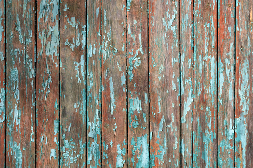 Green old cracked paint on a wooden surface. Background from wooden boards with peeling paint top view. Wooden planks covered with old faded oil paint.