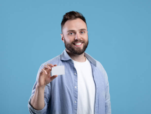 istock Happy young man showing empty business card with space for design over blue studio background 1309258434