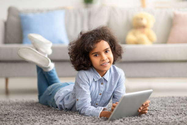 istock Black girl using digital tablet, lying on the floor 1309258508