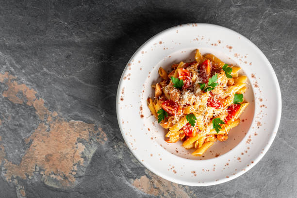 Penne pasta in tomato sauce with chicken on a white plate on stone background. Chicken italian penne pasta. banner, menu recipe place for text, top view Penne pasta in tomato sauce with chicken on a white plate on stone background. Chicken italian penne pasta. banner, menu recipe place for text, top view. chicken rigatoni stock pictures, royalty-free photos & images