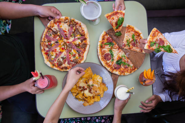 Top view of hands taking pizza and snacks from table in restaurant or cafe. Celebration, party or event concept.