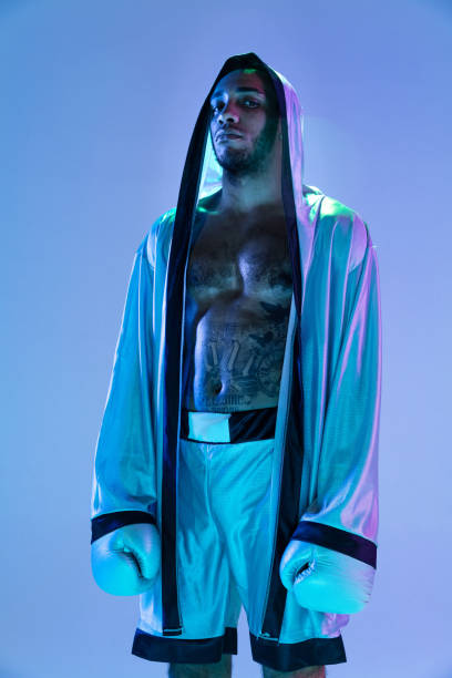 istock High-fashion styled man in white outfit pacticing box isolted over gradient background in neon light 1309260989