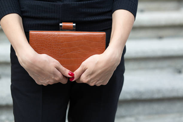 Woman in black apparel holding purse Closeup shot of a woman's hands holding leather brown  bag clutch bag stock pictures, royalty-free photos & images