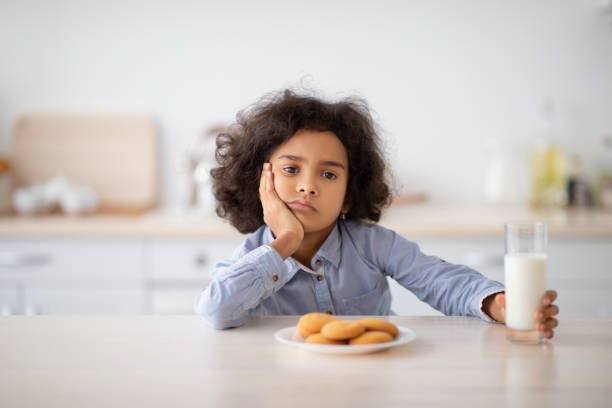 Portrait Of Sad Little Black Girl Holding Glass Of Milk Portrait Of Bored Black Little Girl Sitting At Table With Milk And Cookies, Refuse To Eat Breakfast, Unhappy Kid Resting Head On Hand And Looking Sad, Naughty Child Without Appetite Sitting In Kitchen food allergies stock pictures, royalty-free photos & images