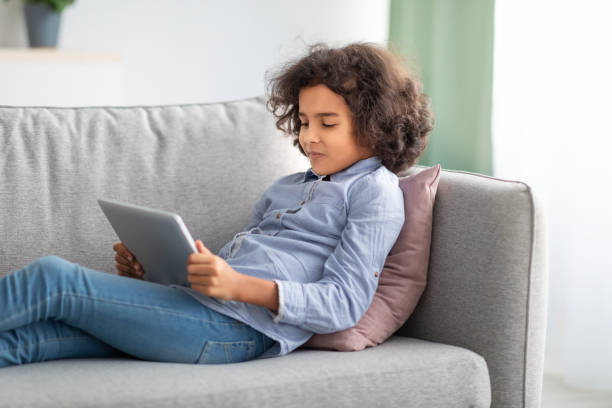 istock Black girl using digital tablet, lying on the couch 1309261602