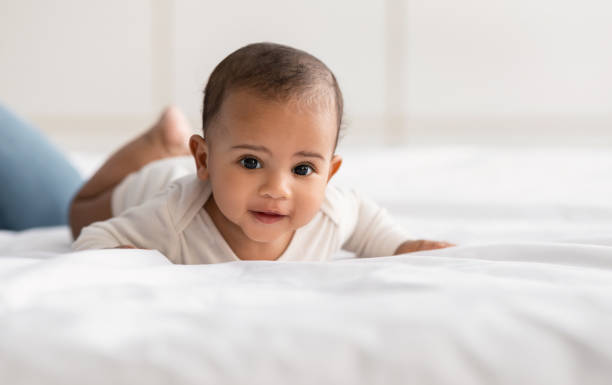 istock Cute little African American infant in bodysuit crawling on bed 1309262275