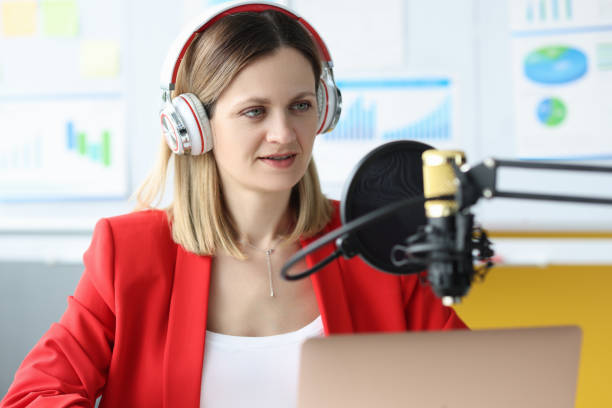 istock Woman with headphones in front of microphone at work table 1309262329