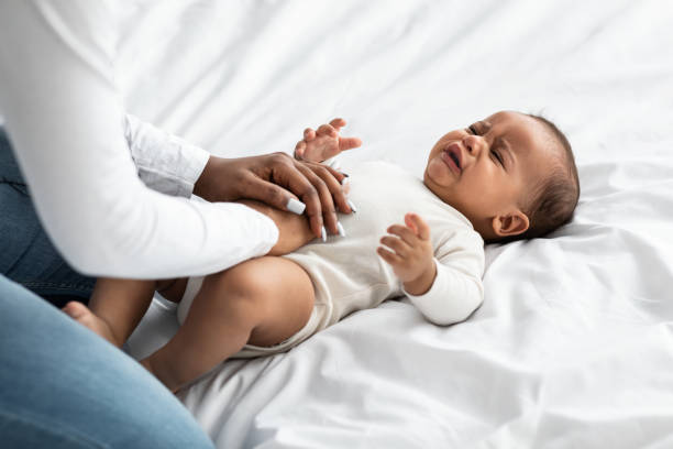 black mother doing belly massage for crying infant - colic imagens e fotografias de stock