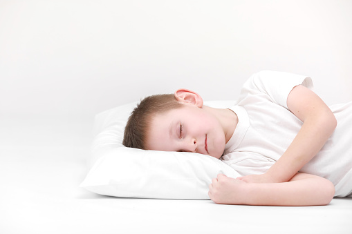 Cute little boy sleeping on the white mattress,