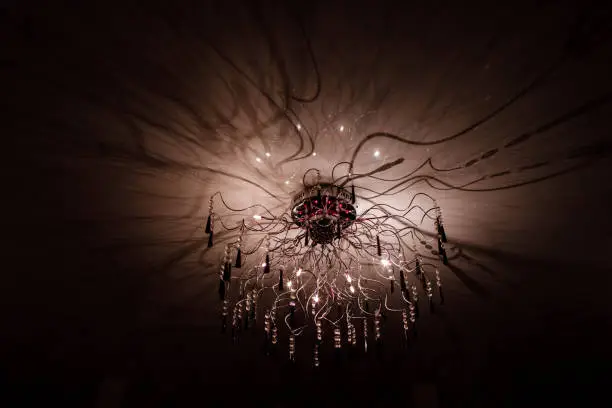 Chandelier.Home, beautiful chandelier.A luxurious lamp hangs from the ceiling. handelier with crystal.Chandelier ceiling lights, black background with copy space.Close Up