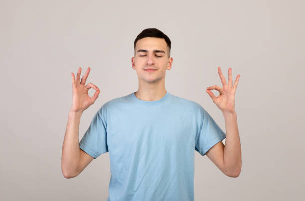 istock Stress management concept. Peaceful young man meditating, finding inner balance and harmony on grey studio background 1309262945
