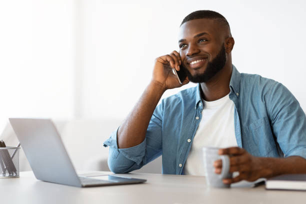 istock Successful black freelancer guy having coffee break at workplace in home office 1309263075