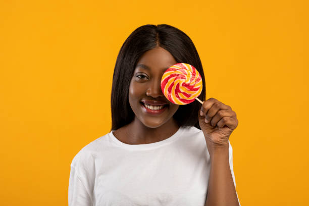 istock Smiling black woman covering her eye with candy 1309263147