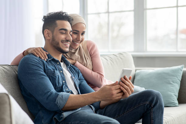 istock Happy middle-eastern couple using mobile phone at home 1309264335