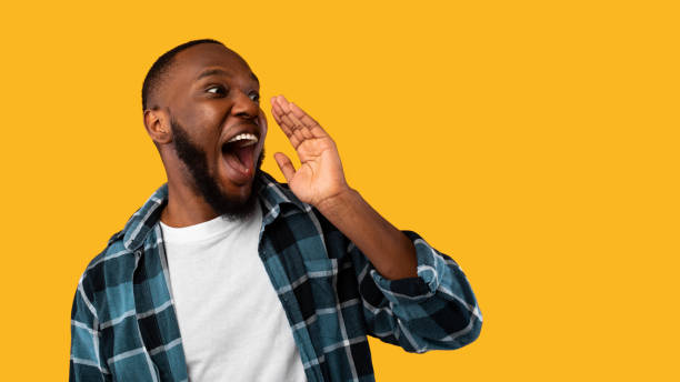 istock Black Guy Shouting Holding Hand Near Mouth Over Yellow Background 1309264393