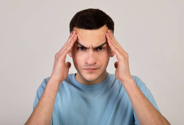 istock Angry young guy massaging his temples, trying to calm down on orange studio background 1309264674
