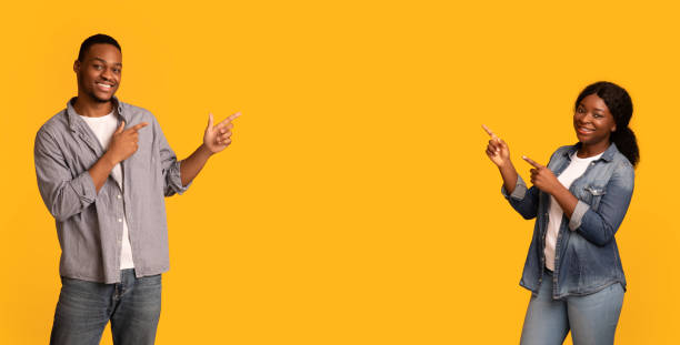 istock Nice Offer. Black couple pointing at copy space in on yellow background 1309264682