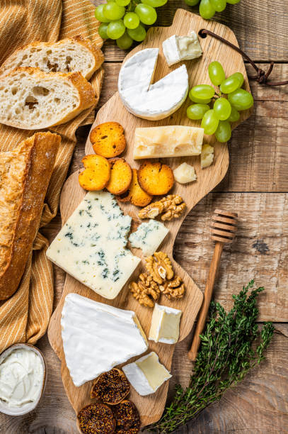 istock Assorted Cheese Brie, Camembert, Roquefort, parmesan, blue cream cheese with grape, fig, bread and nuts. wooden background. Top view 1309264692