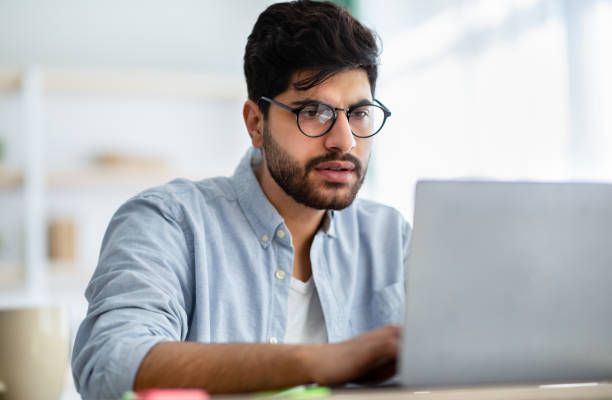 istock Concentrated arabic male freelancer working on laptop at home office, typing on computer keyboard 1309264731