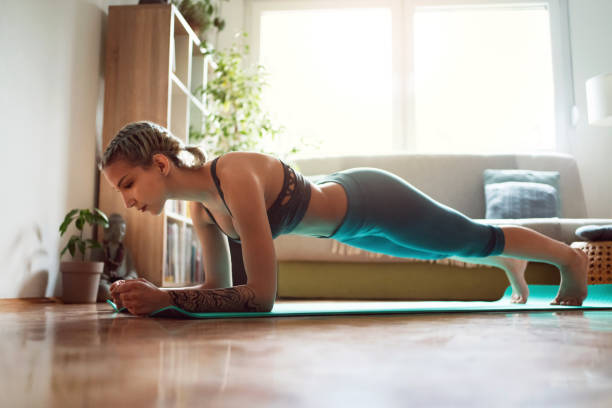 istock Young woman in sportswear practicing at home on her mat, doing plank exercise 1309266449